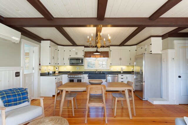 kitchen with white cabinetry, appliances with stainless steel finishes, beam ceiling, light hardwood / wood-style floors, and a chandelier