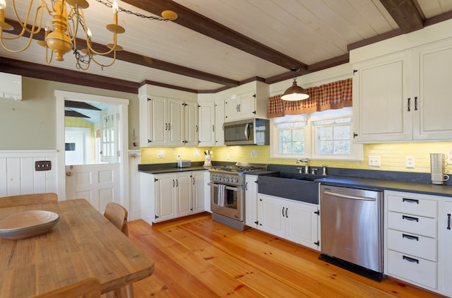 kitchen featuring stainless steel appliances, beam ceiling, an inviting chandelier, light hardwood / wood-style flooring, and white cabinets