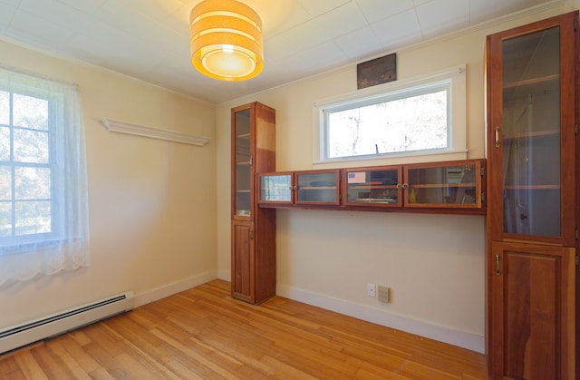 empty room with light wood-type flooring, a baseboard radiator, and crown molding