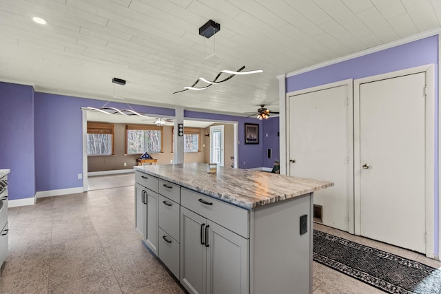 kitchen with gray cabinetry, light stone counters, a kitchen island, pendant lighting, and ceiling fan