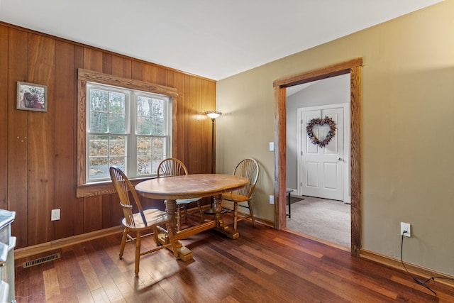 dining space with wooden walls and dark hardwood / wood-style flooring