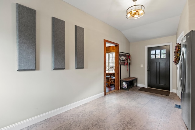 foyer featuring lofted ceiling, an inviting chandelier, and light tile patterned floors