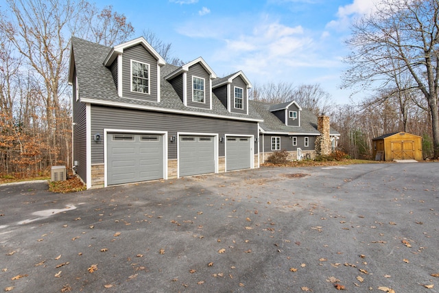 view of side of property with a garage and a storage shed