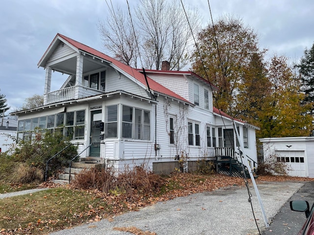 view of front of house featuring a garage, an outdoor structure, and a balcony