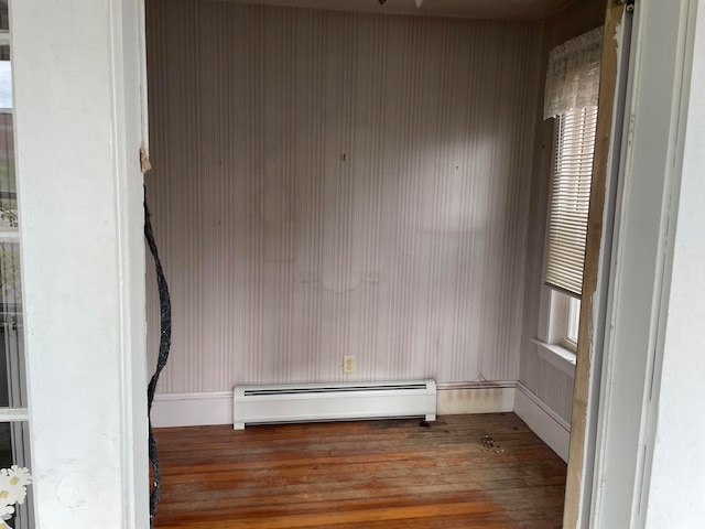 spare room with a baseboard heating unit and wood-type flooring