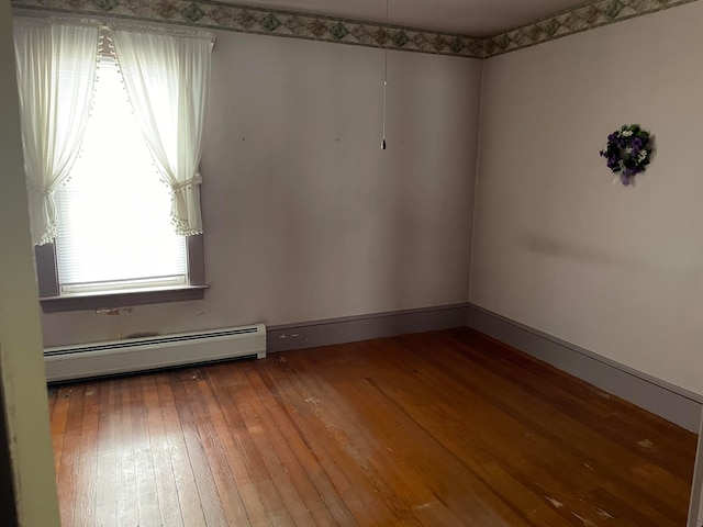 unfurnished room featuring hardwood / wood-style floors and baseboard heating