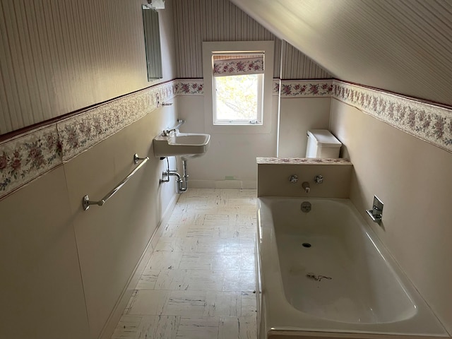 bathroom featuring a bath, sink, and lofted ceiling