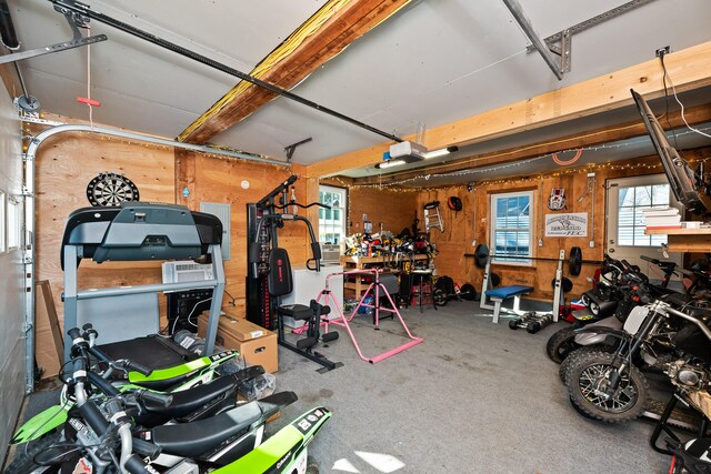 garage featuring a workshop area, wood walls, and a garage door opener