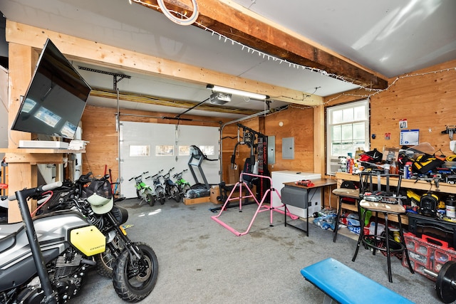 garage with a garage door opener, electric panel, wooden walls, and a workshop area