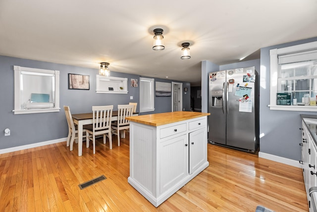 kitchen with white cabinets, light hardwood / wood-style flooring, wood counters, and stainless steel fridge