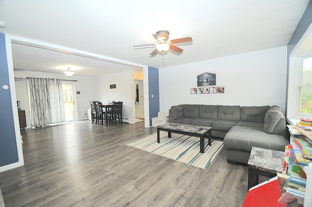 living room with a wall mounted AC, dark hardwood / wood-style floors, and ceiling fan