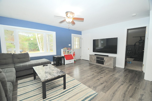 living room featuring dark wood-type flooring, baseboard heating, and ceiling fan