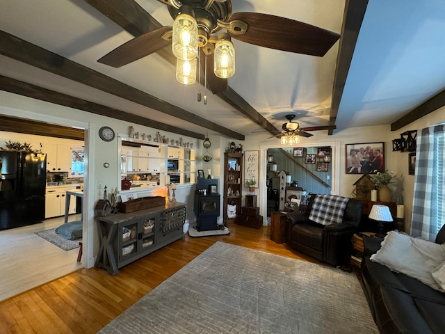 living room with hardwood / wood-style flooring, ceiling fan, and beam ceiling