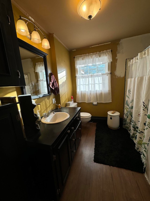 bathroom featuring ornamental molding, walk in shower, vanity, hardwood / wood-style floors, and toilet