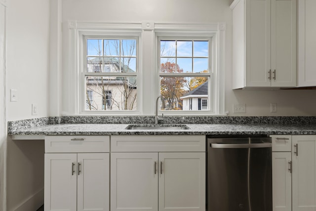 kitchen with dishwasher, sink, dark stone countertops, and white cabinets