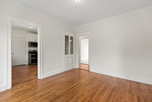 spare room with wood-type flooring and crown molding