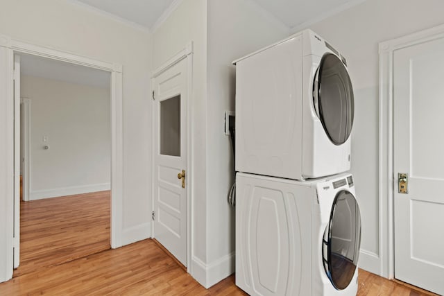 laundry room with stacked washing maching and dryer, crown molding, and light hardwood / wood-style flooring