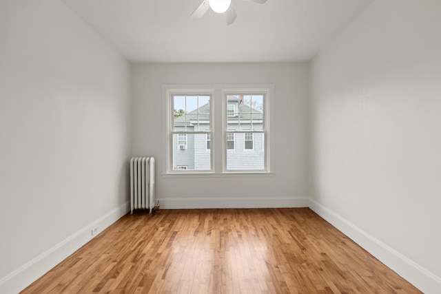 spare room featuring radiator, ceiling fan, and light hardwood / wood-style flooring