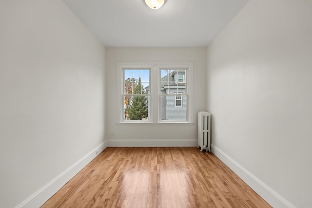 empty room featuring radiator and light hardwood / wood-style flooring