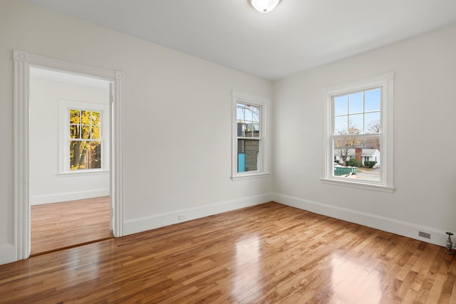 unfurnished room featuring a wealth of natural light and hardwood / wood-style floors