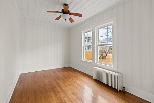 spare room with light wood-type flooring, ceiling fan, crown molding, and radiator