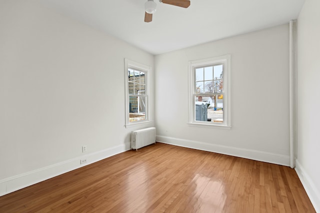 unfurnished room featuring ceiling fan, wood-type flooring, and radiator heating unit