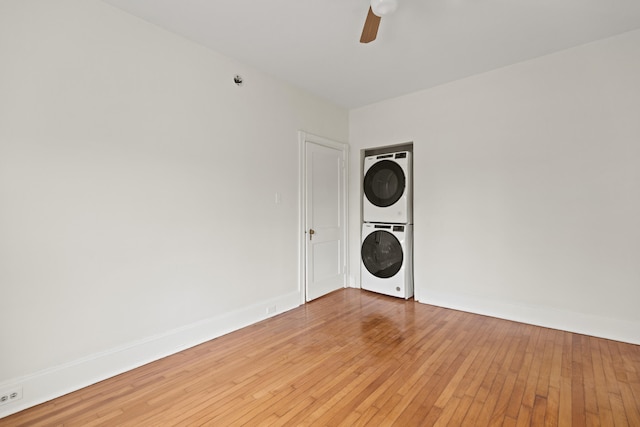 clothes washing area with hardwood / wood-style floors, stacked washer and dryer, and ceiling fan