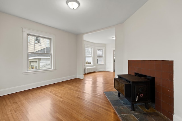 living room featuring wood-type flooring, radiator heating unit, and a wood stove