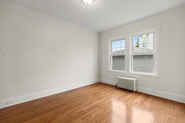 empty room featuring radiator and light hardwood / wood-style flooring