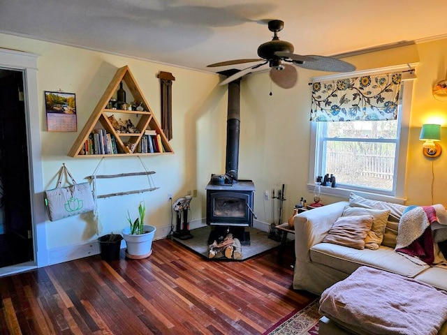 living room with a wood stove, ornamental molding, hardwood / wood-style flooring, and ceiling fan