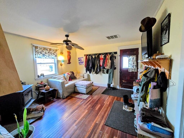 living room featuring a wood stove, plenty of natural light, wood-type flooring, and ceiling fan