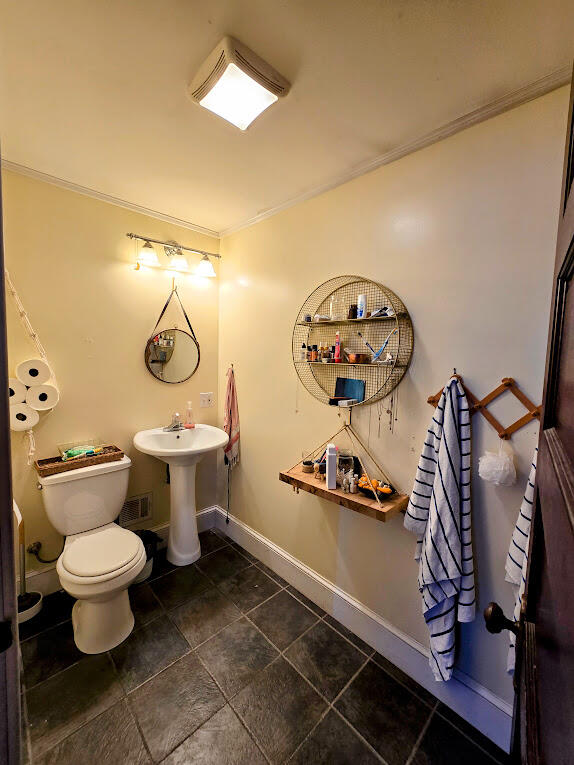 bathroom with toilet, tile patterned floors, and ornamental molding