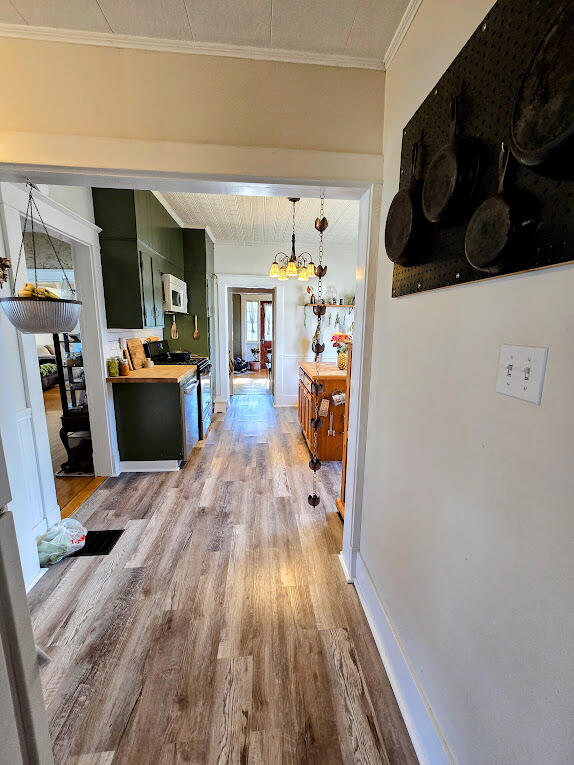 corridor with wood-type flooring and crown molding