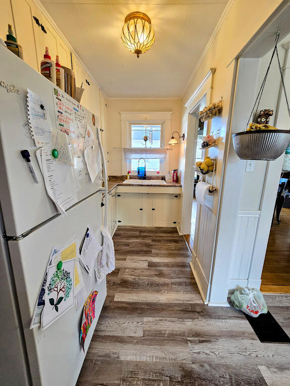 kitchen featuring sink, dark hardwood / wood-style floors, crown molding, white cabinets, and white refrigerator