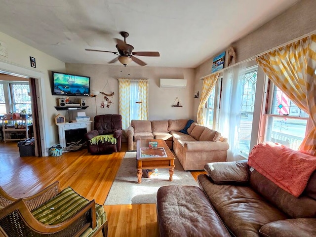 living room with a wall mounted air conditioner, hardwood / wood-style flooring, and ceiling fan