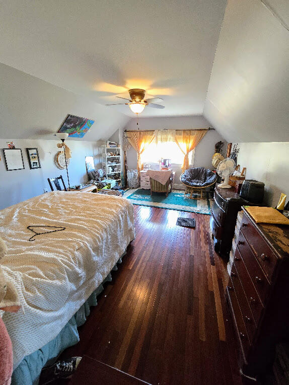 bedroom with dark hardwood / wood-style flooring, lofted ceiling, and ceiling fan