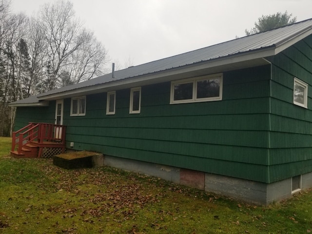 view of side of home featuring a yard and a wooden deck