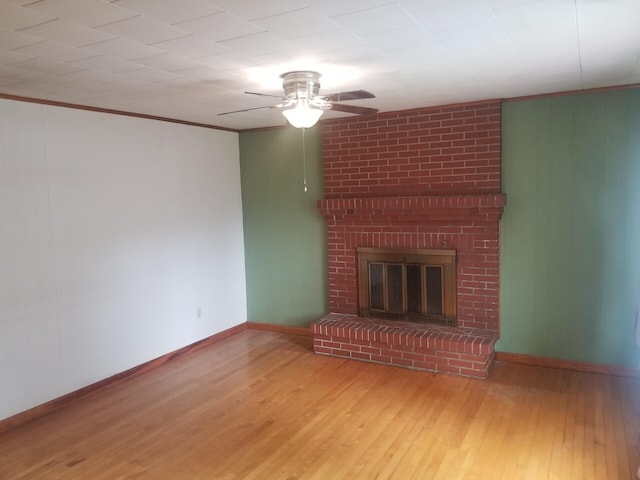 unfurnished living room with a brick fireplace, crown molding, ceiling fan, and hardwood / wood-style flooring