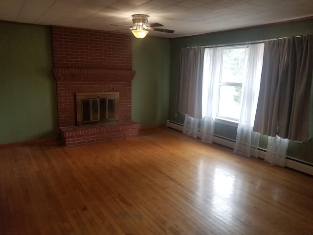 unfurnished living room with ceiling fan, a fireplace, a baseboard radiator, and light wood-type flooring