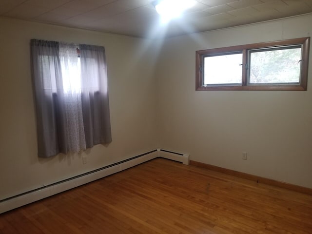 empty room with hardwood / wood-style floors and baseboard heating