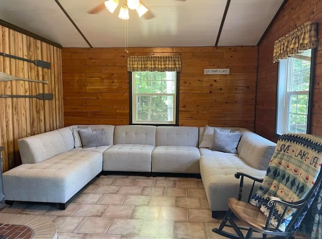 living room with wood walls, ceiling fan, and lofted ceiling