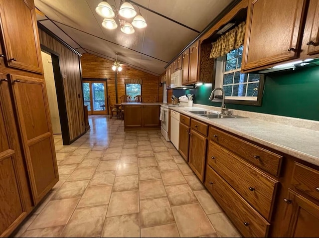 kitchen featuring wooden walls, decorative light fixtures, vaulted ceiling, and sink