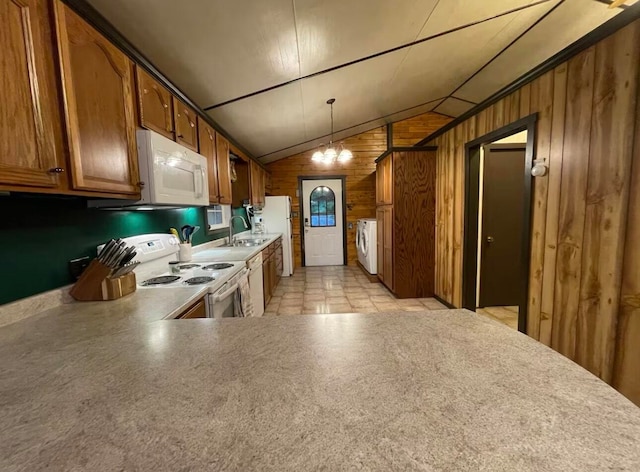 kitchen featuring wood walls, sink, decorative light fixtures, white appliances, and vaulted ceiling