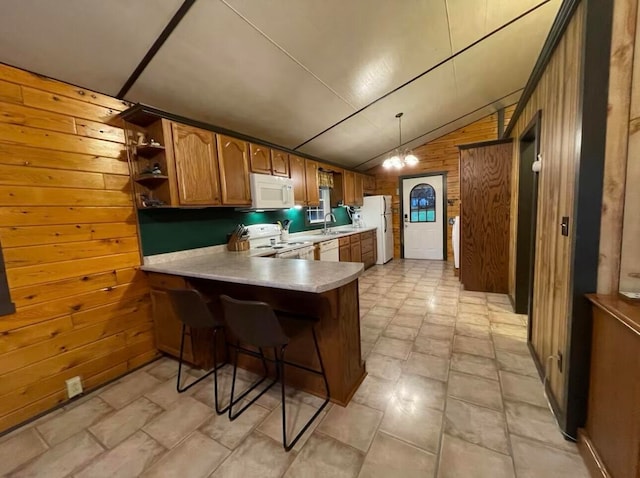 kitchen with wood walls, kitchen peninsula, decorative light fixtures, white appliances, and lofted ceiling