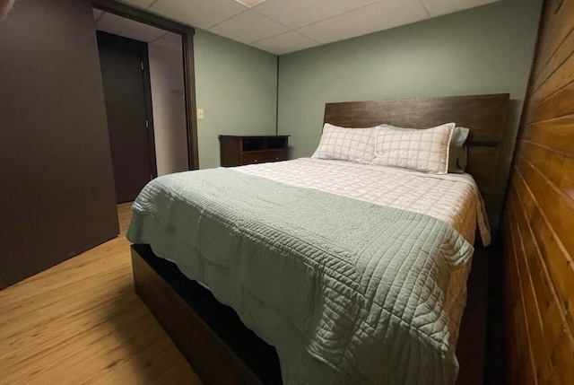 bedroom with hardwood / wood-style floors and a paneled ceiling