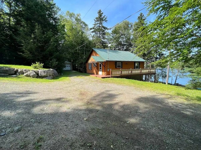 view of home's exterior featuring a garage, an outbuilding, and a deck with water view