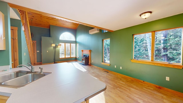 kitchen featuring a wall unit AC, sink, and hardwood / wood-style flooring