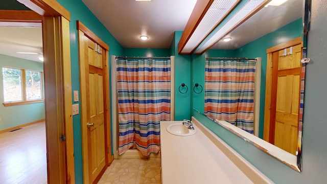 bathroom with wood-type flooring, shower / bath combination with curtain, ceiling fan, and sink