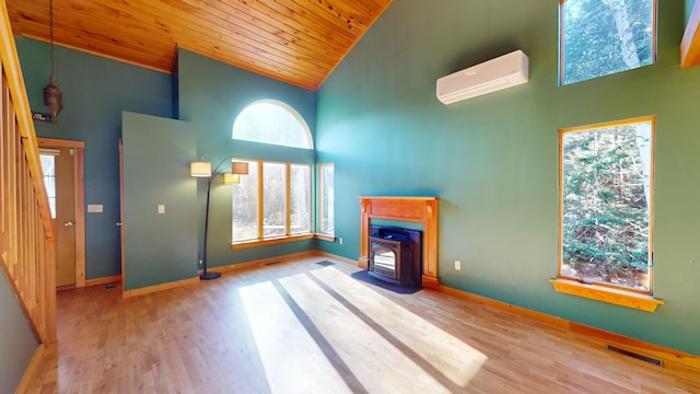 unfurnished living room featuring a wood stove, a wall mounted air conditioner, and a healthy amount of sunlight