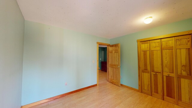 unfurnished bedroom with light hardwood / wood-style flooring and a closet